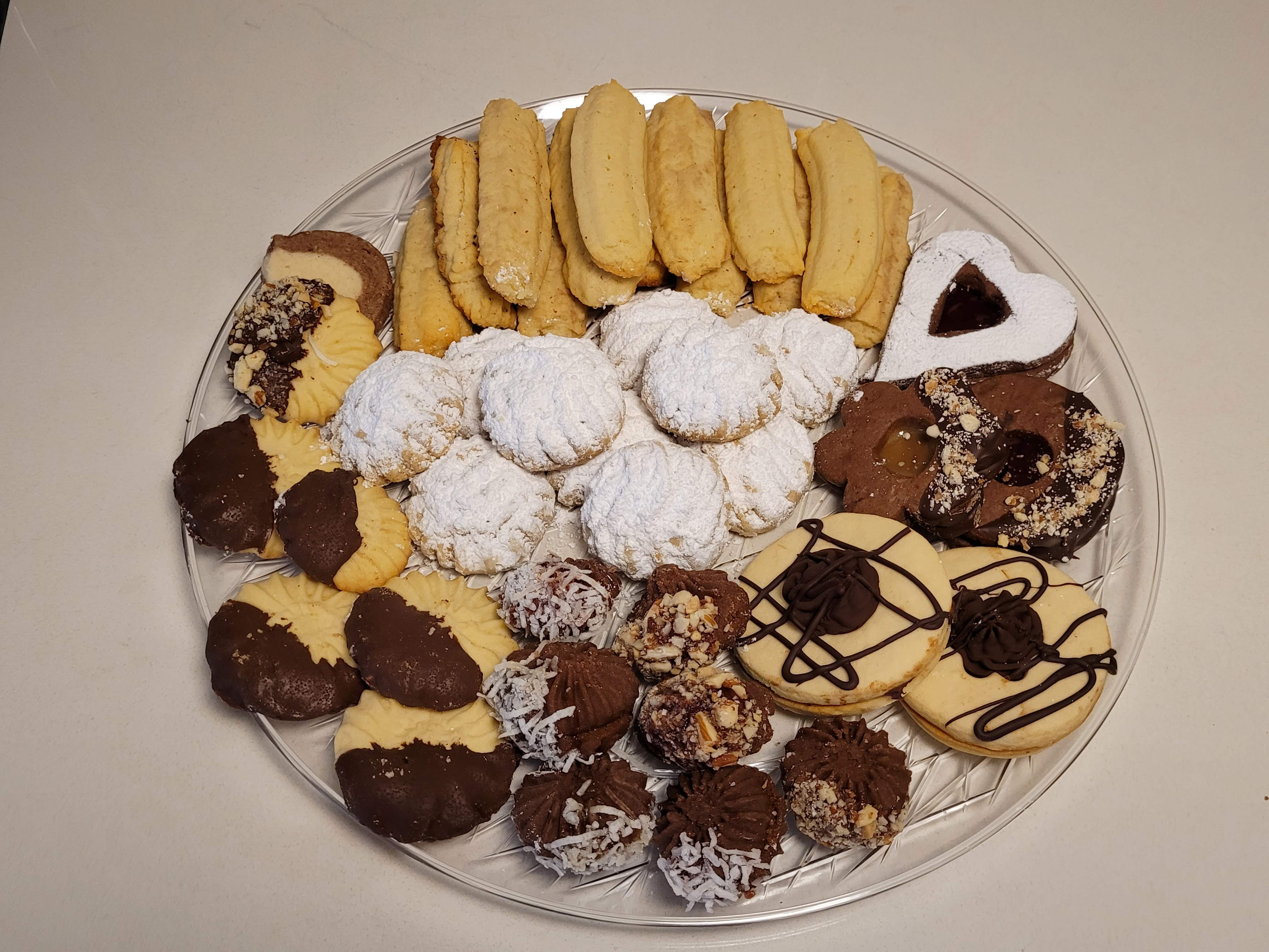 Round platter of assorted Middle Eastern desserts — Kahk with powdered sugar, chocolate-dipped petit four, different shaped Ghorayeba, Laksheir and Nashader biscuits